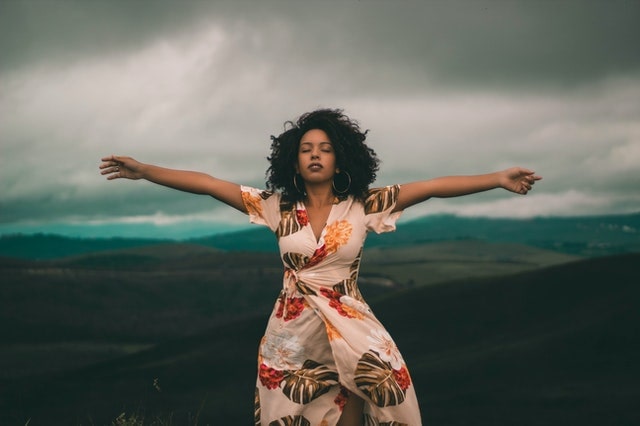 black woman standing in front of cloudy landscape