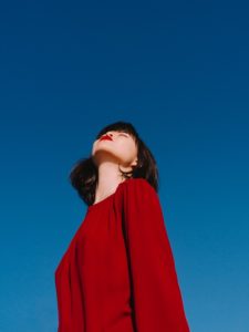Asian woman with red lipstick against blue sky