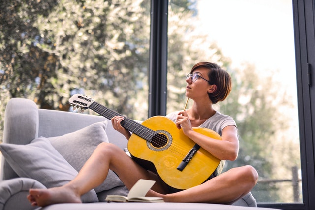 white woman writing a song with guitar