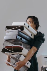 Asian woman carrying stack of binders