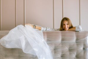 white woman unwrapping plastic covering on couch