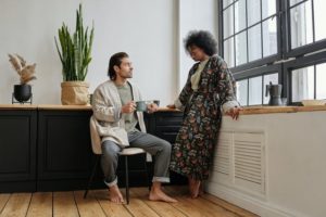 black woman and man of color talking near windows