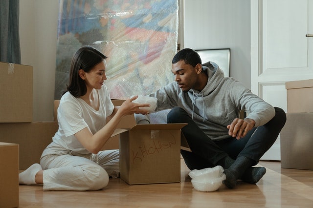 diverse couple packing belongings in boxes