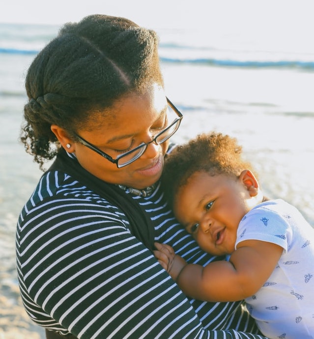 black mother holding baby on the beach