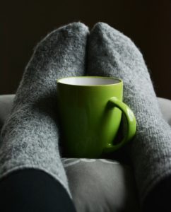 feet in warm socks holding a mug