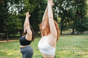 two white women doing yoga in a park