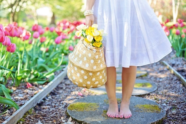 barefoot woman holding basket of flowers