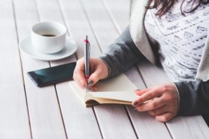 white woman's hands writing in journal