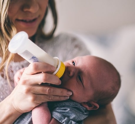 white mother feeding baby bottle