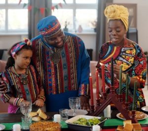 Family celebrating kwanzaa with woman lighting candles