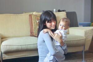 mom holding baby in front of couch