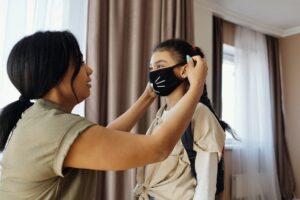 black woman putting mask on young girl