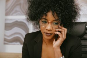 black woamn in suit with glasses talking on a cell phone reaching out to a therapist